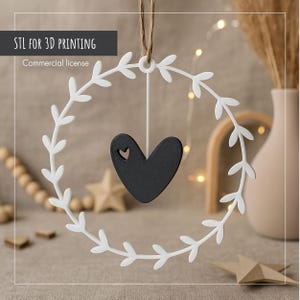 May include: A white, leaf-shaped wreath with a black heart pendant. The heart has a small cutout. The wreath is suspended by a string. The text "STL FOR 3D PRINTING" and "Commercial license" are in the upper left corner.