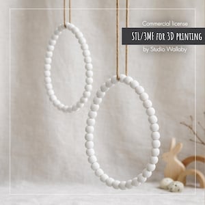 May include: Two white beaded oval ornaments suspended by twine. The ornaments are crafted from small, round beads. The image also features text: "Commercial license STL/3MF FOR 3D PRINTING by Studio Wallaby".