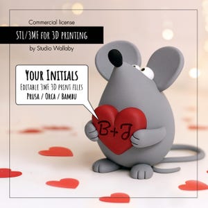 May include: A gray mouse figurine holding a red heart with the initials "B+J". The image includes text that says "STL/3MF FOR 3D PRINTING" and "YOUR INITIALS". The mouse has large ears and a long tail. Red heart-shaped confetti is scattered around the base.