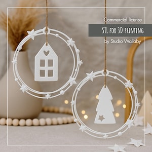 Op de afbeelding: Twee witte kerstversieringen. Eén heeft een huisvorm met een hart en ramen, de andere een boomvorm met een ster. Beide zitten in een cirkelvormige lijst met sterren en kralen. De tekst "STL FOR 3D PRINTING" is zichtbaar.