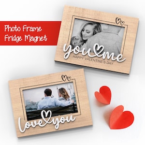 May include: Two wooden photo frames with a white background. The top frame has the text "you & me" with a heart symbol and "Happy Valentine's Day" below. The bottom frame has the text "love you" with a heart symbol. Both frames have a cutout heart design in the top corner.
