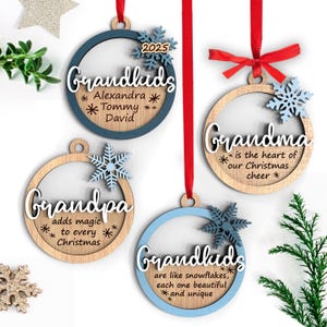 Puede incluir: Cuatro adornos navideños de madera con cintas rojas. Los adornos tienen un diseño circular con el texto "Grandkids", "Grandma", "Grandpa" y "Grandkids". Cada adorno tiene un diseño de copo de nieve y está en tonos de azul y madera natural.