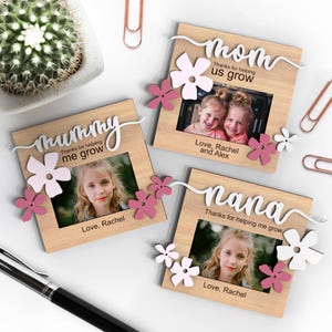 May include: Three wooden photo frames with pink and white flowers and the words "mom", "mummy", and "nana" with the text "Thanks for helping us grow" or "Thanks for helping me grow".