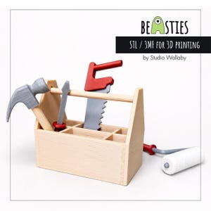 May include: A wooden toy toolbox containing a hammer, saw, and screwdriver. A paint roller is to the right. The toolbox has the text "BEASTIES" and "STL / 3MF FOR 3D PRINTING by Studio Wallaby".
