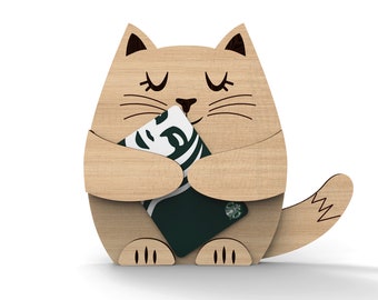 Puede incluir: Una figurita de gato de madera sosteniendo una tarjeta de regalo Starbucks verde. El gato tiene los ojos cerrados y una expresión feliz.