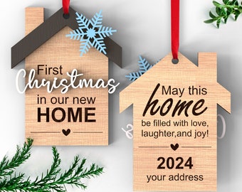 May include: Two wooden house-shaped ornaments with a red ribbon. The first ornament says "First Christmas in our new HOME" with a blue snowflake. The second ornament says "May this home be filled with love, laughter, and joy! 2024 your address".