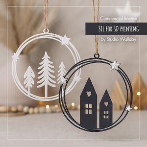 Könnte beinhalten: Zwei Weihnachtsschmuckstücke mit kreisförmigem Design. Eines ist weiß mit einer Waldszene, das andere ist schwarz mit Haussilhouetten. Beide haben Sternakzente und sind mit Schnur aufgehängt. Der Text lautet "STL FOR 3D PRINTING".