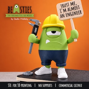 Pode incluir: Uma figura de monstro verde de um olho só, usando um capacete amarelo, calções azuis e ténis brancos. Segura um paquímetro cinzento e uma placa de madeira com a inscrição TRUST ME, I'M ALMOST AN ENGINEER. Uma pequena engrenagem cinzenta está pousada ao lado.