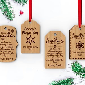 May include: Four wooden Christmas ornaments with a red ribbon. The ornaments are engraved with the text "Santa's Magic Key" and "Dear Santa". One ornament has the text "We have no chimney as you can see, so please use this magic key to leave our presents under the tree. Love, David".