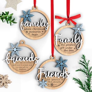 Peut inclure: Ornements de Noël en bois avec les mots "Famille" et "Amis" en écriture blanche. Chaque ornement a un flocon de neige et un ruban rouge pour l'accrocher. Les ornements sont de couleur marron clair.