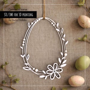 Può includere: Decorazione pasquale bianca a forma ovale con dettagli floreali e fogliari, sospesa da uno spago. Il design include un grande fiore in basso. Il testo "STL/3MF FOR 3D PRINTING" è visibile. Uova di Pasqua sullo sfondo.