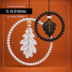 May include: Two hanging circular ornaments featuring white and black spherical beads. The larger white hoop holds a white oak leaf cutout, while the smaller black hoop contains a black leaf cutout. Text reads: Commercial license STL FOR 3D PRINTING by Studio Wallaby.