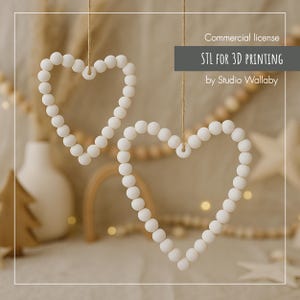 Op de afbeelding: Twee witte hartvormige decoraties van kralen, hangend aan touw. De harten zijn gemaakt van kleine, ronde kralen en hangen tegen een zachte, neutrale achtergrond. De afbeelding bevat de tekst "STL FOR 3D PRINTING by Studio Wallaby."