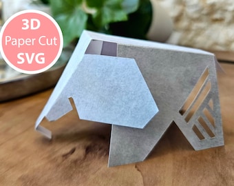 May include: A 3D paper cut design of a geometric shape, with a light gray color and intricate cutouts. The design is labeled "3D Paper Cut SVG".