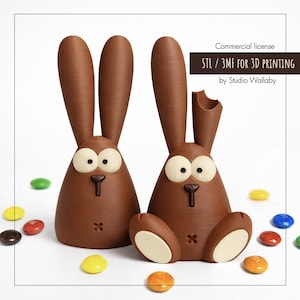 May include: Two brown bunny figurines with large ears, big eyes, and a bite taken out of one ear. The bunnies are surrounded by colorful candies. The image includes the text "STL / 3MF FOR 3D PRINTING by Studio Wallaby".