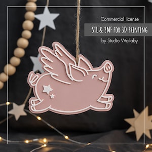 May include: A pink flying pig decoration with white detailing and a star. It hangs from a natural twine string. The image includes text: "Commercial license STL & 3MF FOR 3D PRINTING by Studio Wallaby."