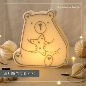 May include: A bear-shaped night light emitting a warm glow, holding a star with star cutouts. The light has a gray outline. Text at the bottom reads "STL & 3MF FOR 3D PRINTING". The words "Commercial license" are at the top.