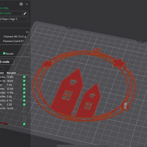 K&ouml;nnte beinhalten: Eine 3D-Drucker-Oberfl&auml;che zeigt ein rotes Design von zwei H&auml;usern mit herzf&ouml;rmigen Ausschnitten, umgeben von einem sternenbesetzten Oval. Die Oberfl&auml;che zeigt Druckzeit, Filamentl&auml;nge und Kosten. Das Design befindet sich auf einem grauen Raster.