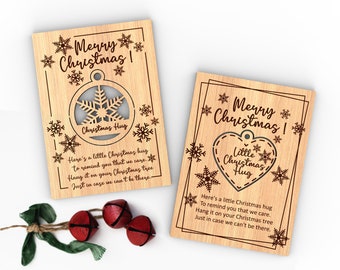 May include: Two wooden Christmas cards with a snowflake and heart cutout. The cards have the text "Merry Christmas!" and "Here's a little Christmas hug to remind you that we care. Hang it on your Christmas tree. Just in case we can't be there."