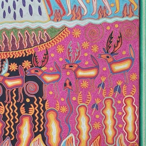 May include: A colorful, hand-stitched textile art piece depicting a scene with stylized figures and animals. The background is a vibrant blue with yellow dots, and the foreground features a pink landscape with deer and other creatures. The artwork is framed with a green border.