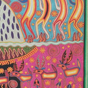 May include: A colorful, hand-stitched artwork depicting a scene with stylized figures. The top portion features four figures with long necks and antlers, standing on a blue background with white and yellow accents. The bottom portion features a pink background with stylized deer and plants.