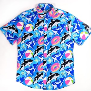 May include: A blue short-sleeved button-down shirt with a colorful print of orcas, donuts, and beach balls.