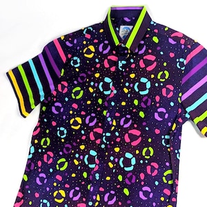 May include: A short-sleeved button-down shirt with a black background and a colorful leopard print. The sleeves have a striped pattern in yellow, green, blue, and purple.