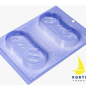 May include: A clear plastic mold for making two chocolate game controllers. The mold is light blue and has the words "04 PORTO FORMAS" printed on it.