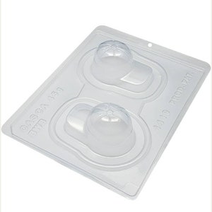 May include: A clear plastic mold for making chocolate baseball caps. The mold has two cavities and the text "CASCA 439 BWB" and "1418 PROD. PAT." is visible.
