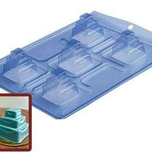 May include: A clear plastic mold for making six tiered cake pops. The mold is blue and has a textured surface. The mold is designed to create six cake pops, each with three tiers.