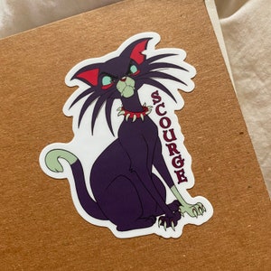 May include: A sticker featuring a cartoon cat with a menacing expression. The cat is primarily dark purple with red accents on its ears and collar. The word "SCURGE" is written vertically in red. The cat has green eyes and claws.