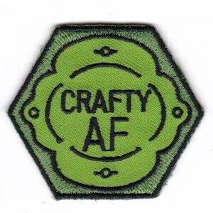 May include: A green and black embroidered patch with the text "CRAFTY AF" in black. The patch has a unique shape with a green border and a lighter green center, perfect for crafters and DIY enthusiasts.