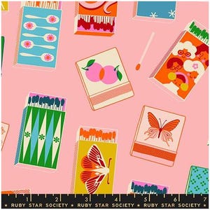 May include: Pink fabric with a repeating pattern of matchboxes. The matchboxes feature various designs, including spoons, butterflies, and people. The text "RUBY STAR SOCIETY" is at the bottom.