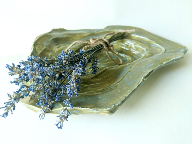 May include: A green ceramic dish with a textured surface, featuring a bouquet of dried lavender tied with twine.