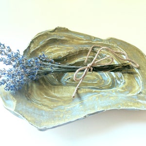 May include: A green and blue ceramic dish with a rough, textured surface. A bundle of dried lavender is tied with twine and placed in the dish.