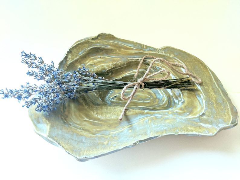 May include: A green and blue ceramic dish with a rough, textured surface. A bundle of dried lavender is tied with twine and placed in the dish.
