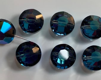 May include: Seven round, faceted, dark blue glass beads with a hole through the center. The beads have a iridescent finish.