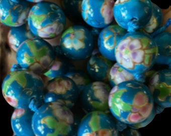 Könnte beinhalten: Eine Nahaufnahme einer blauen und weißen Perlenkette mit Blumenmustern. Die Perlen sind rund und haben eine glänzende Oberfläche. Die Kette ist aus Keramik und hat einen zarten, femininen Look.