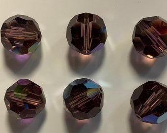 May include: Six iridescent purple glass beads with a faceted design. The beads are round and have a hole in the center for stringing.