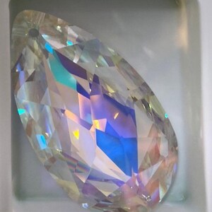 May include: A clear iridescent teardrop-shaped crystal pendant with a hole at the top for hanging.
