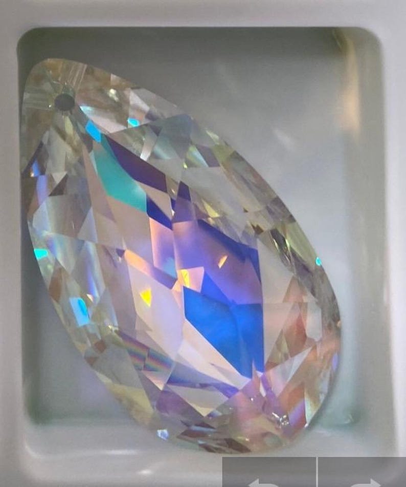 May include: A clear iridescent teardrop-shaped crystal pendant with a hole at the top for hanging.