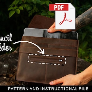 以下が含まれることがあります： 前面に「Pencil holder」と書かれたジッパー付きポケットが付いた、茶色の革製のタブレットケース。ケースが開いており、タブレットが挿入されています。画像には「PDF」というテキストとPDFアイコンが含まれています。