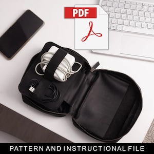 May include: A black zippered pouch with a white laptop charger and cords inside. The pouch is open and the interior is black. A white laptop keyboard and a black smartphone are also in the image. The text "PDF" is in red on a white background with a red Adobe Acrobat logo.