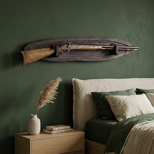 Könnte beinhalten: Ein langes Vorderladergewehr im antiken Stil mit Holzschaft und Messingbeschlägen, das horizontal auf einer dunklen, ovalen und geschichteten Holz-Wandplatte montiert ist. Das Gewehr verfügt über einen metallischen Schlossmechanismus und einen langen Lauf.