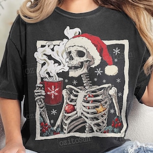 May include: Black t-shirt featuring a skeleton wearing a Santa hat, holding a red mug with a snowflake design. The skeleton is decorated with a candy cane, star, and holly. The shirt has the text "ozitosun".