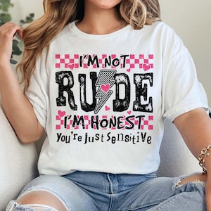 May include: White t-shirt with a pink and black graphic that says "I'm not rude I'm honest you're just sensitive".