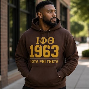 Peut inclure: Un sweat-shirt à capuche marron foncé avec un texte imprimé en doré indiquant Iota Phi Theta, les lettres grecques IΦΘ et le nombre 1963. Ce vêtement à enfiler possède une poche kangourou à l'avant, des manches longues et des cordons assortis.