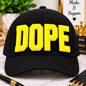 May include: A black baseball cap featuring the word DOPE in large, bright yellow, textured, three-dimensional letters across the front panels. The cap has a structured crown, a curved brim, and stitched eyelets on the top panels for ventilation.