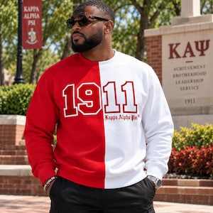 May include: A crewneck sweatshirt featuring a split-color design with a solid red left side and a solid white right side. The front displays the large red text 1911 and the smaller red text Kappa Alpha Psi printed on the white section.