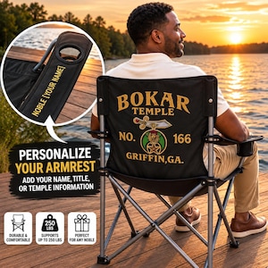 May include: A black folding camping chair with a metal frame, featuring the gold embroidered text BOKAR TEMPLE NO. 166 GRIFFIN, GA. The armrest includes a cup holder and space for custom text, with a weight capacity of 250 lbs indicated.